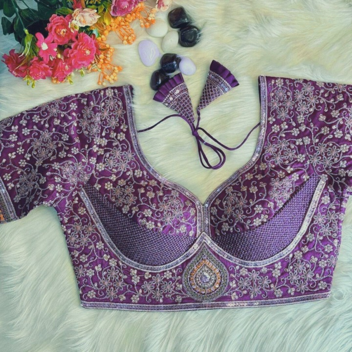 Purple embroidered blouse with floral decorations on a white surface