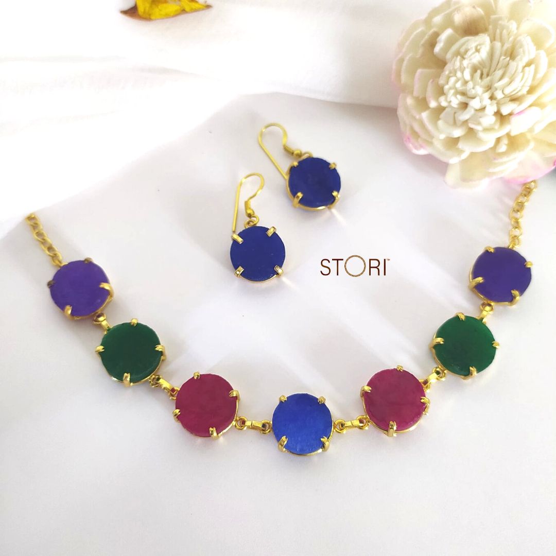 Multi-color stone necklace with raw stone craftsmanship and blue earrings.