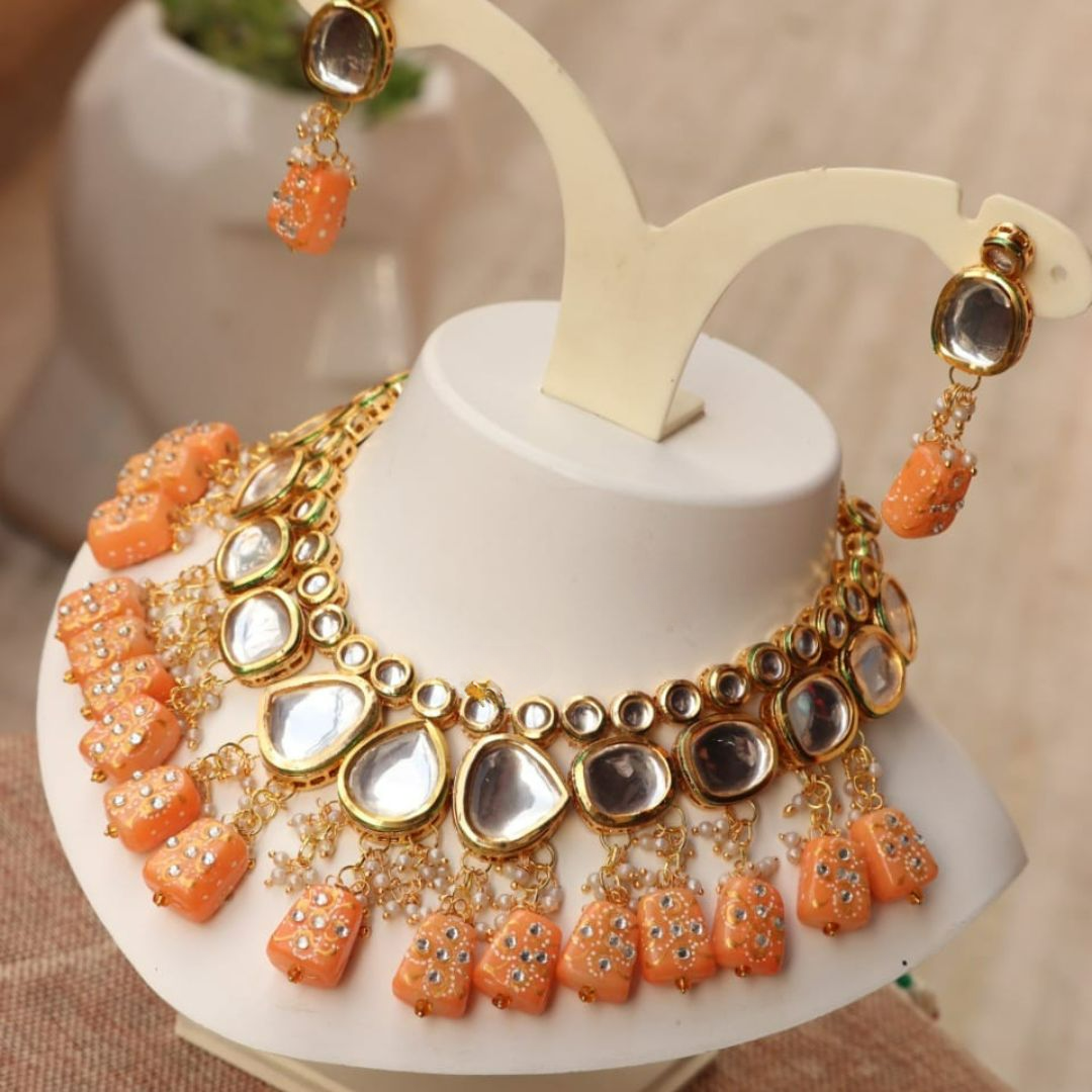 Orange kundan necklace with a Tanjore-inspired design.