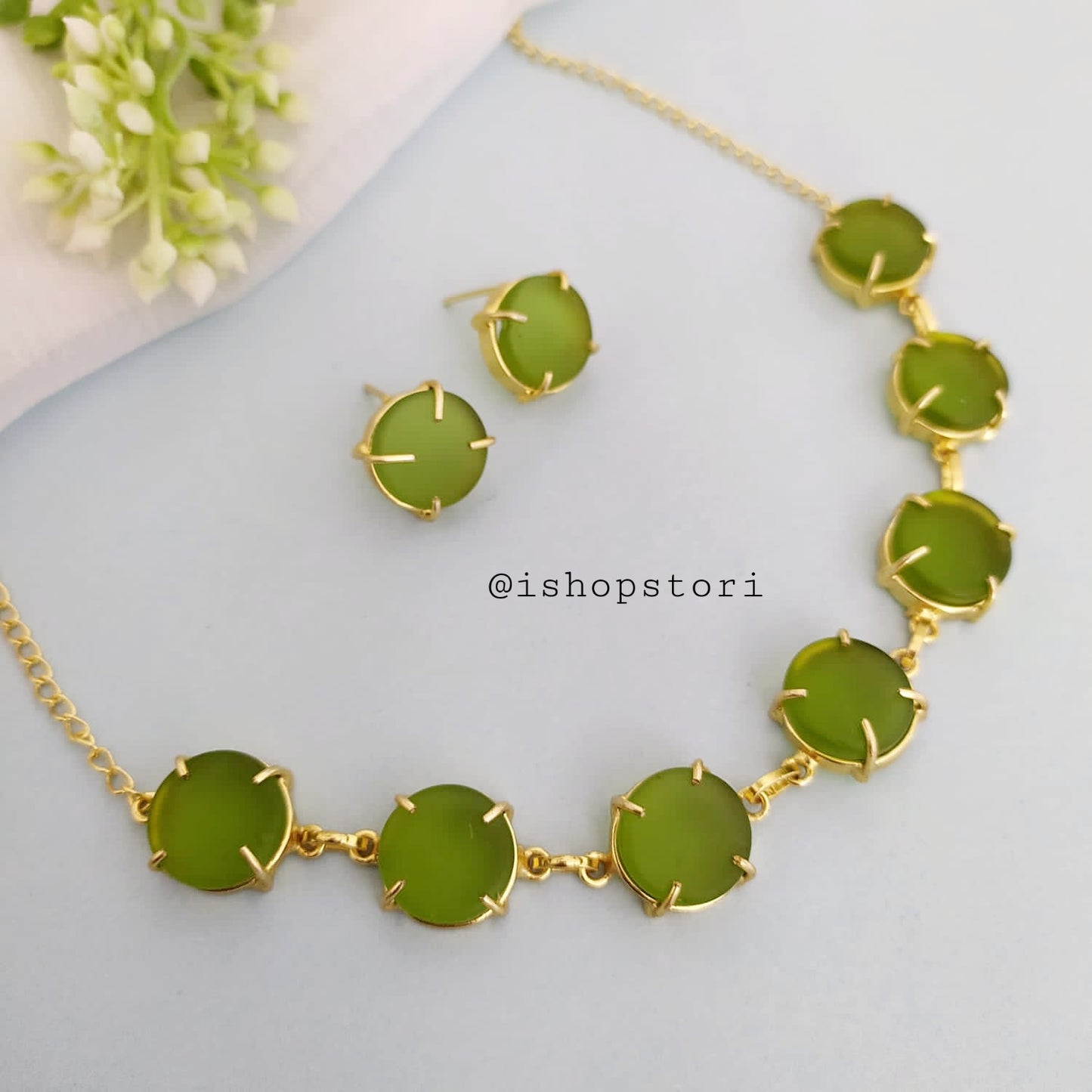 Elegant gold necklace design with single-color raw stones and green earrings.