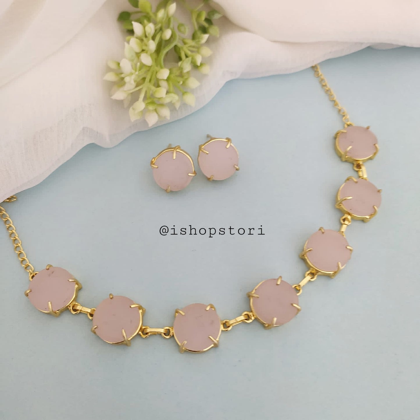 Elegant gold necklace design with single-color raw stones and green earrings.
