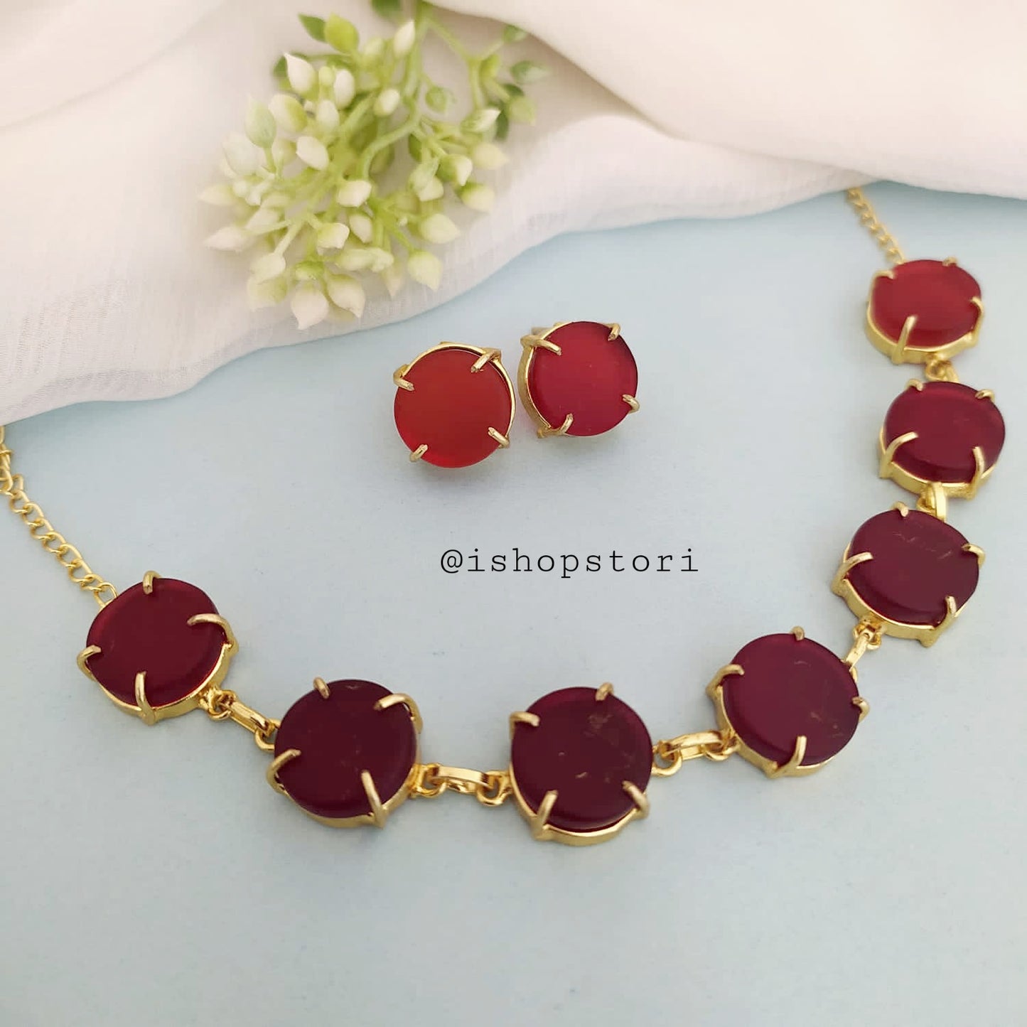 Elegant gold necklace design with single-color raw stones and green earrings.