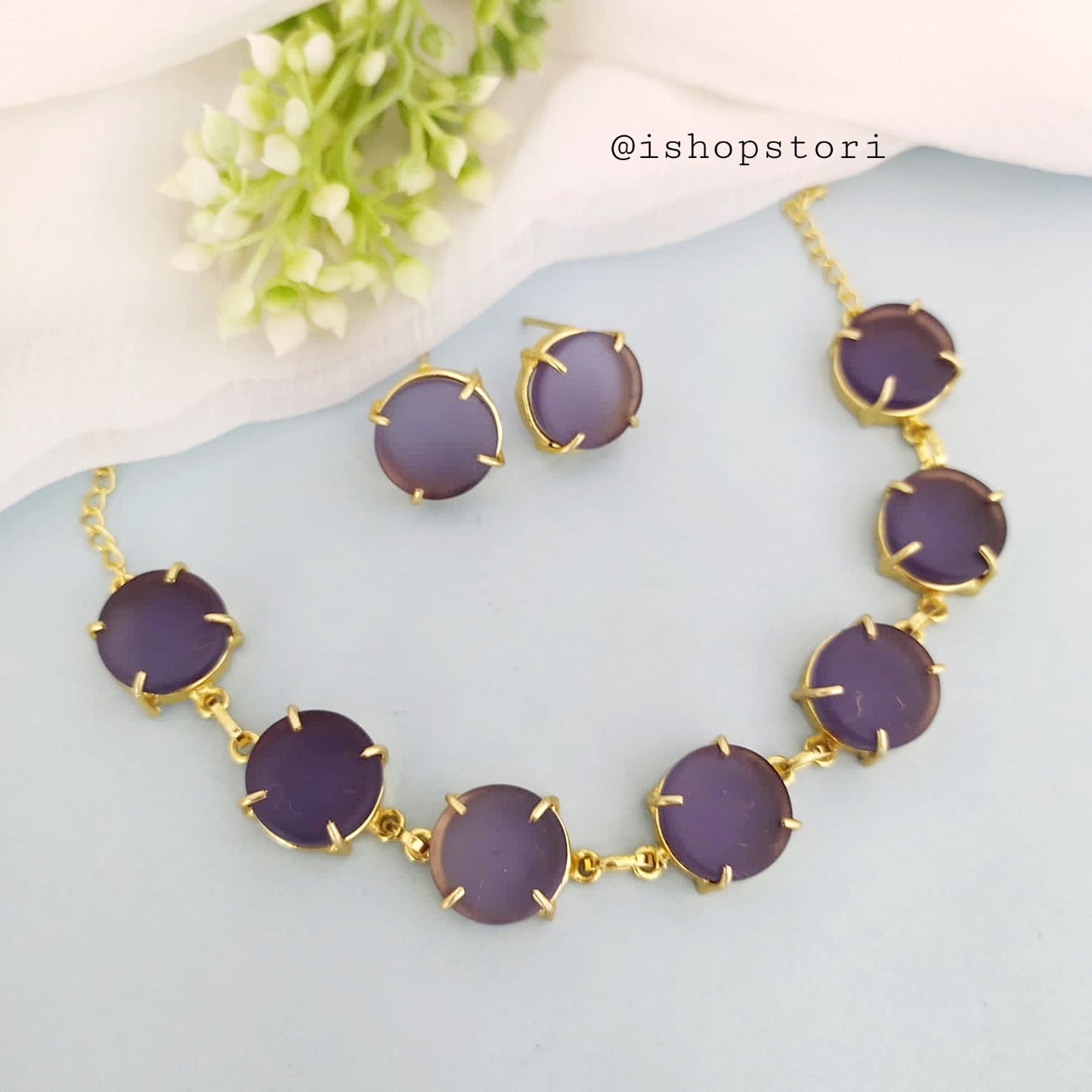 Elegant gold necklace design with single-color raw stones and green earrings.