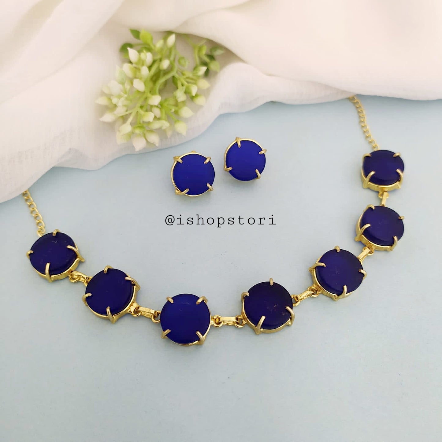 Elegant gold necklace design with single-color raw stones and green earrings.