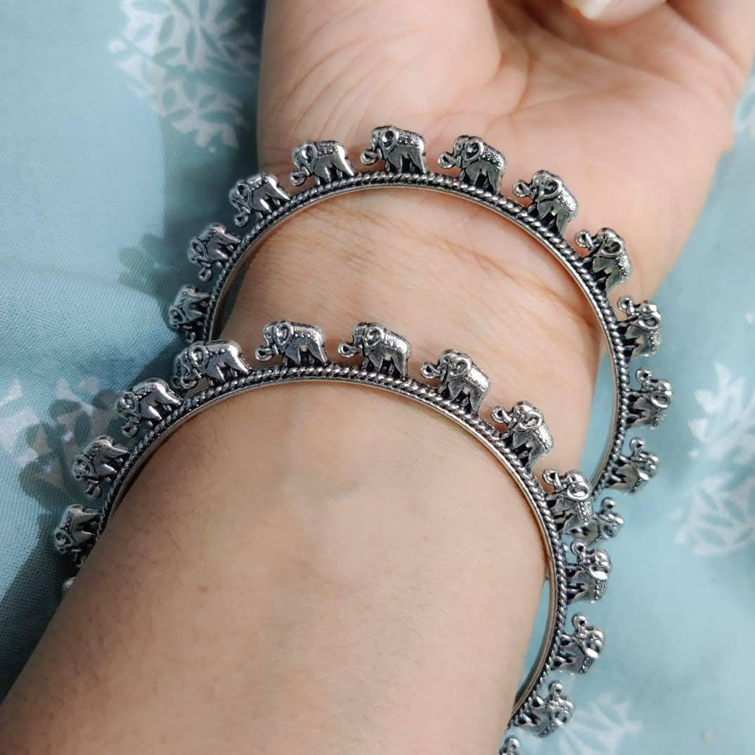 Silver bracelet with elephant design on a wrist against a light blue background