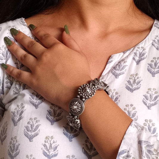 Close-up of a person wearing a silver bracelet on a white patterned garment.