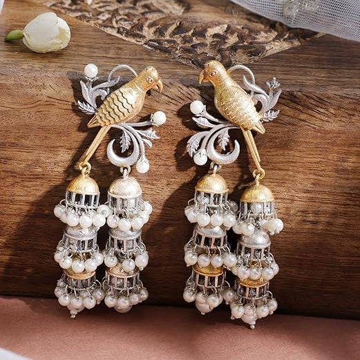 Ornate earrings with bird designs on a wooden surface