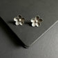 Pair of silver flower earrings on a dark surface