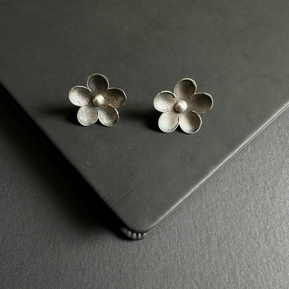 Pair of silver flower earrings on a dark surface