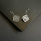 Pair of silver earrings on a dark surface