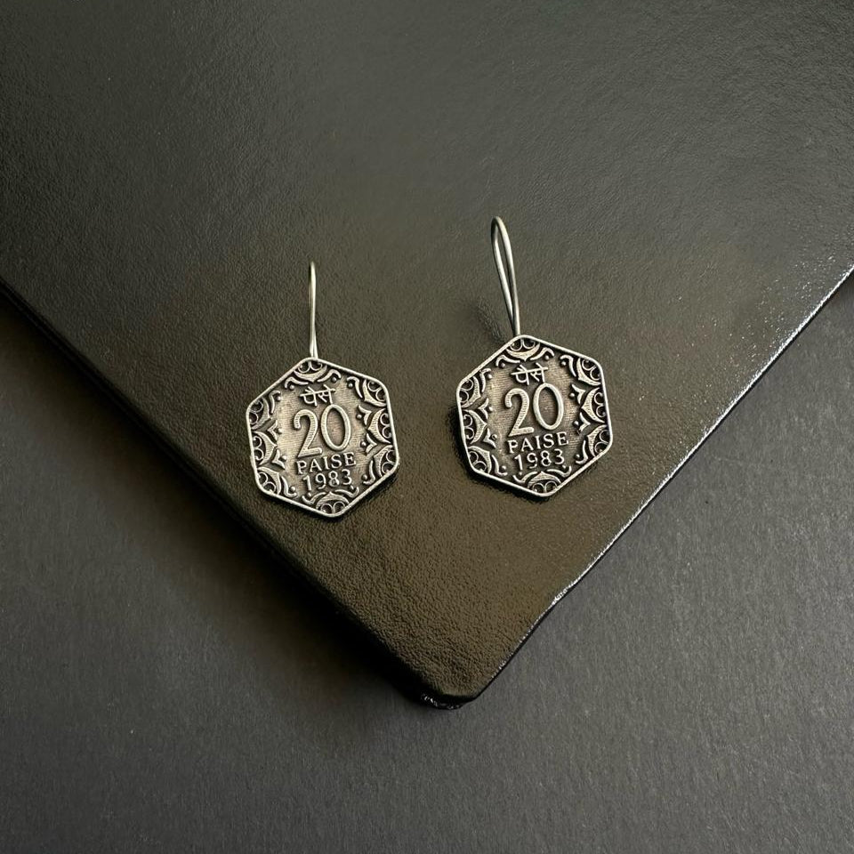 Hexagonal silver earrings on a dark surface