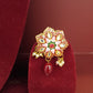 Decorative gold ring with gemstones and a red bead on a red velvet stand.