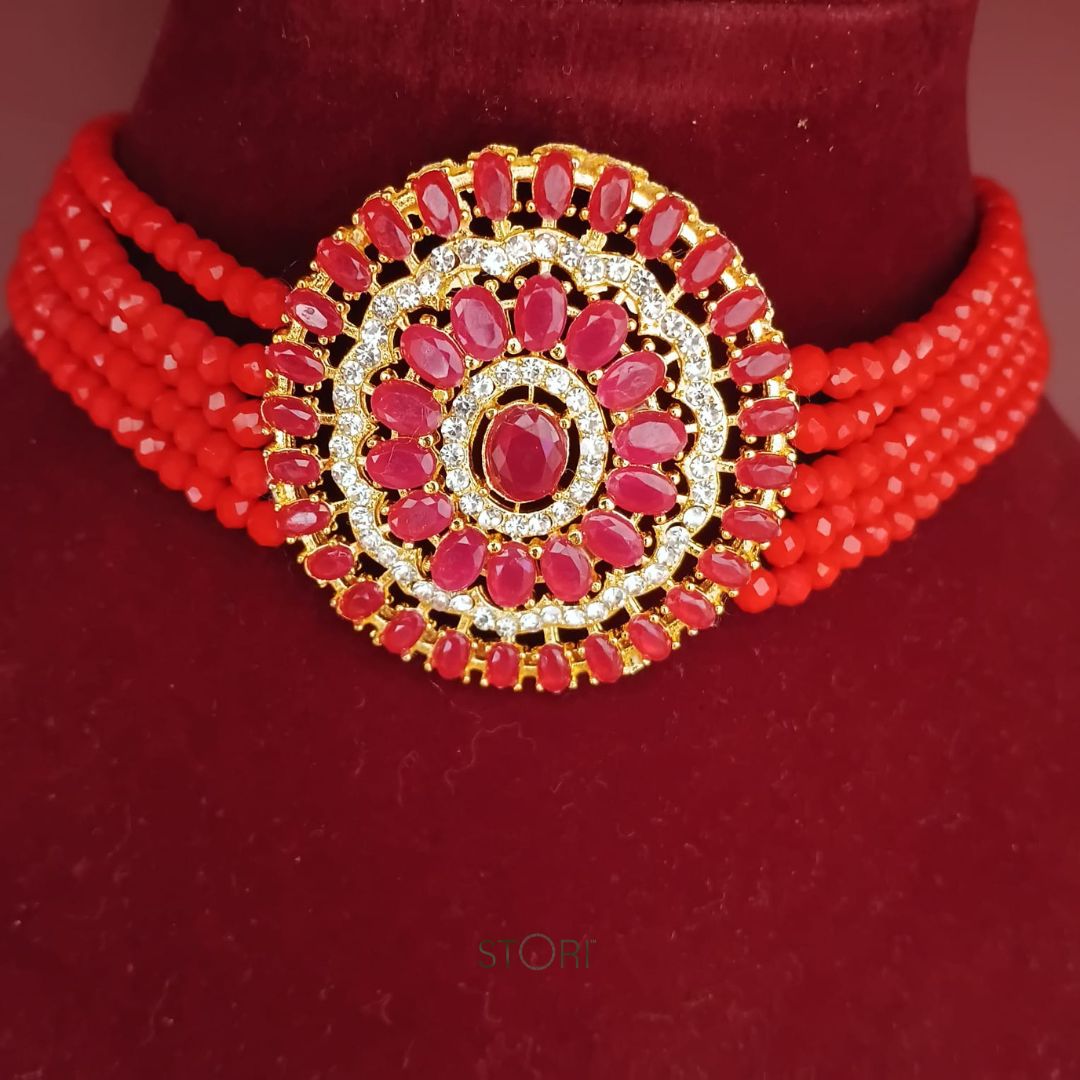 Red beaded necklace with a gold and red central pendant on a red background