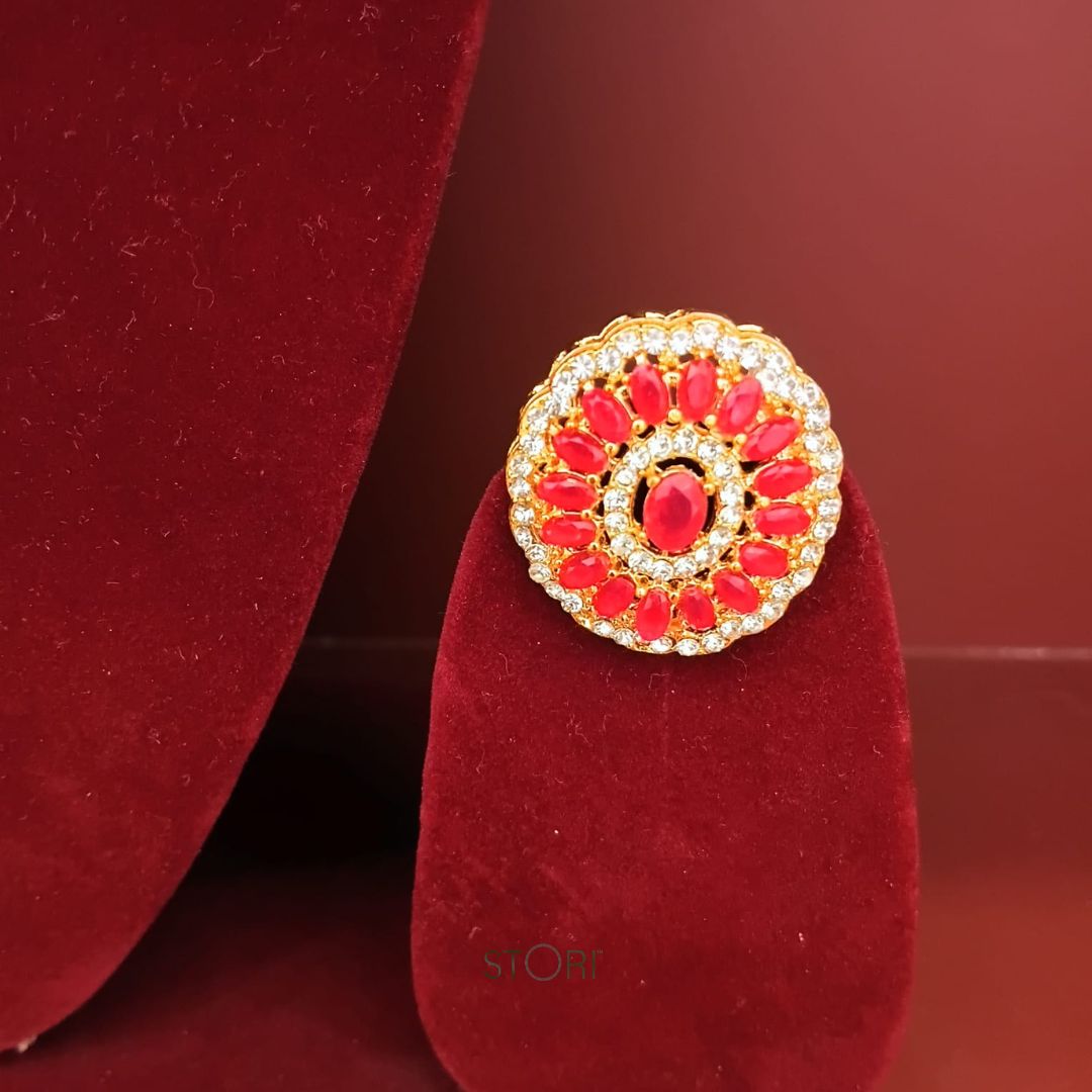 Gold ring with red gemstones on a red velvet stand