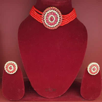 Red beaded necklace and earrings set on a red velvet stand.
