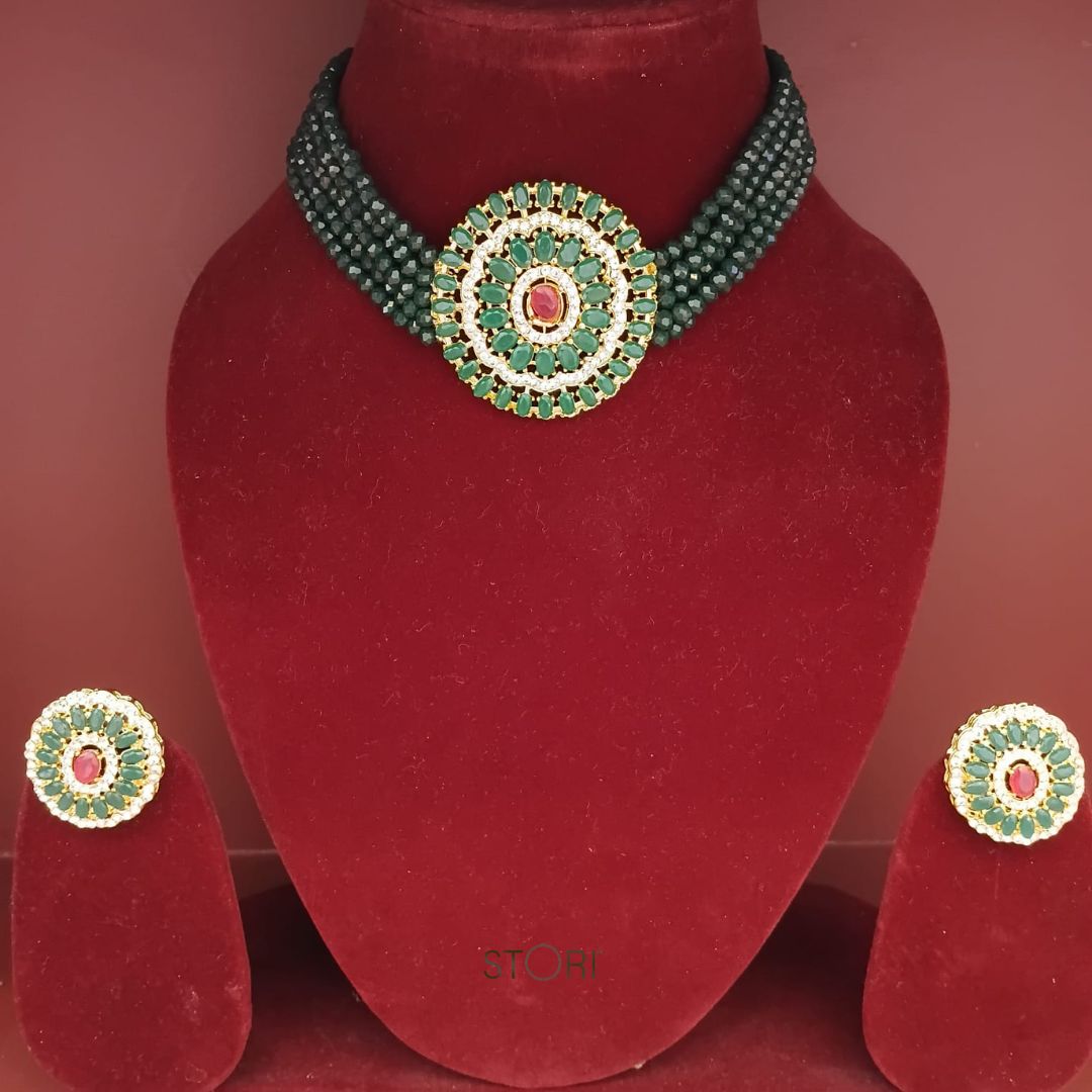 Green beaded necklace and earrings on a red velvet stand with 'TONI' branding.