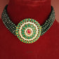 Green beaded necklace with a circular green gemstone pendant on a red background