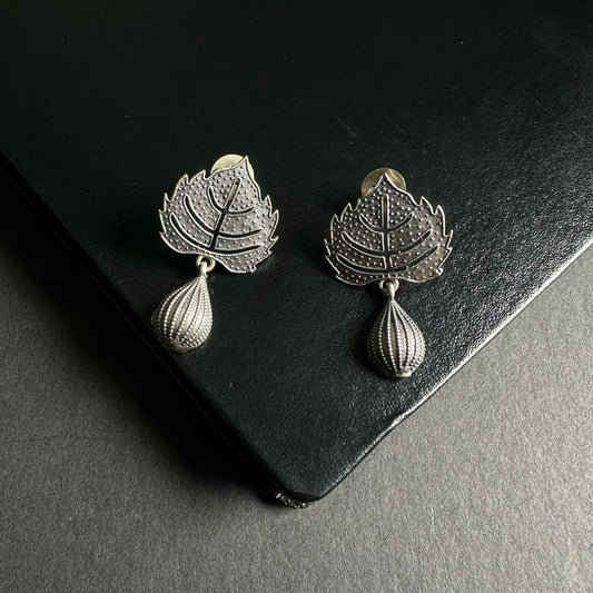 Pair of silver leaf earrings on a dark surface