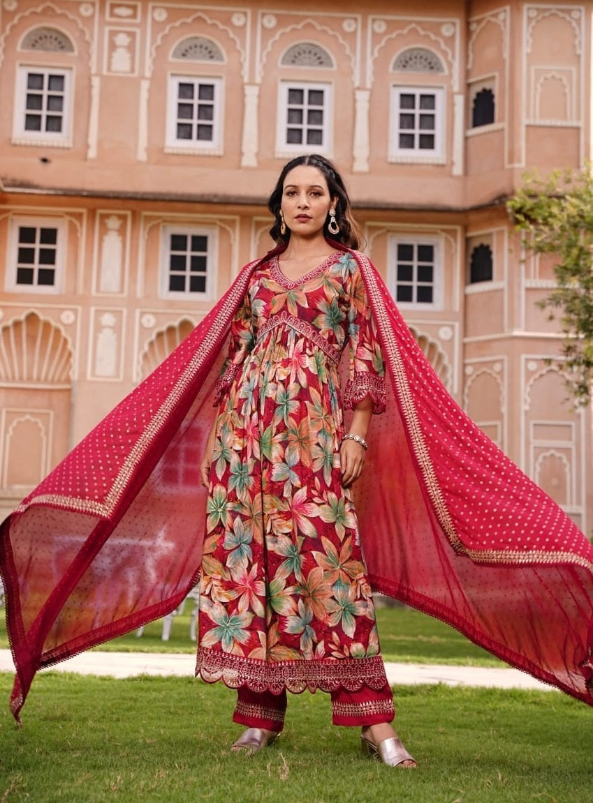 Woman in traditional outfit with a red dupatta in front of a pink building