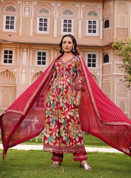 Woman in traditional outfit with a red dupatta in front of a pink building