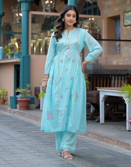 Woman in a light blue traditional outfit standing outdoors.