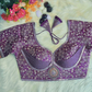 Purple embroidered blouse with floral decorations on a white surface