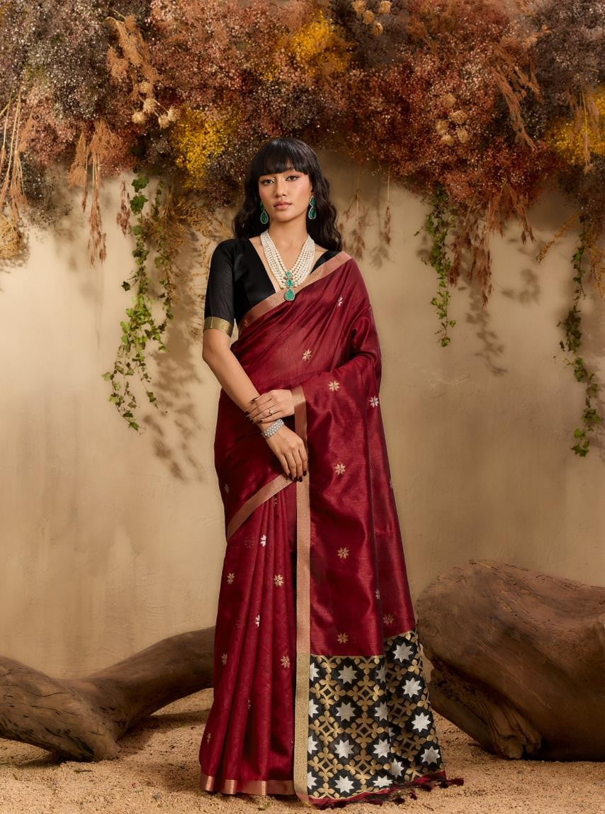 Woman in a maroon saree with a black blouse against a natural backdrop