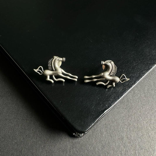 Pair of silver earrings with horse design on a black background