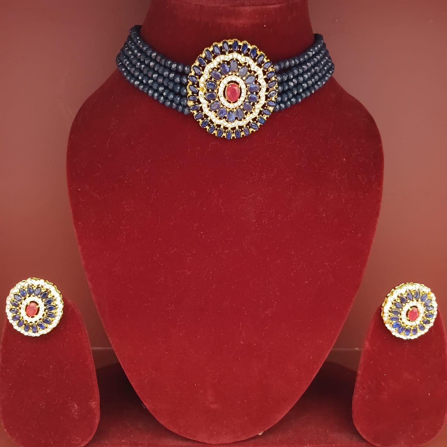 Jewelry set with a necklace and earrings on a red velvet stand.