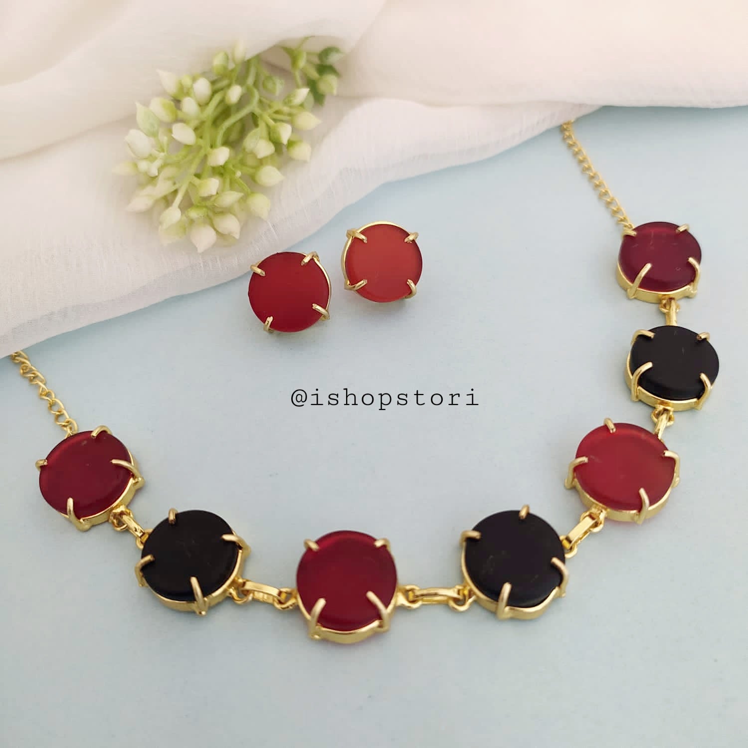 Multi-color raw stone claw necklace in a stylish design with dark red earrings.