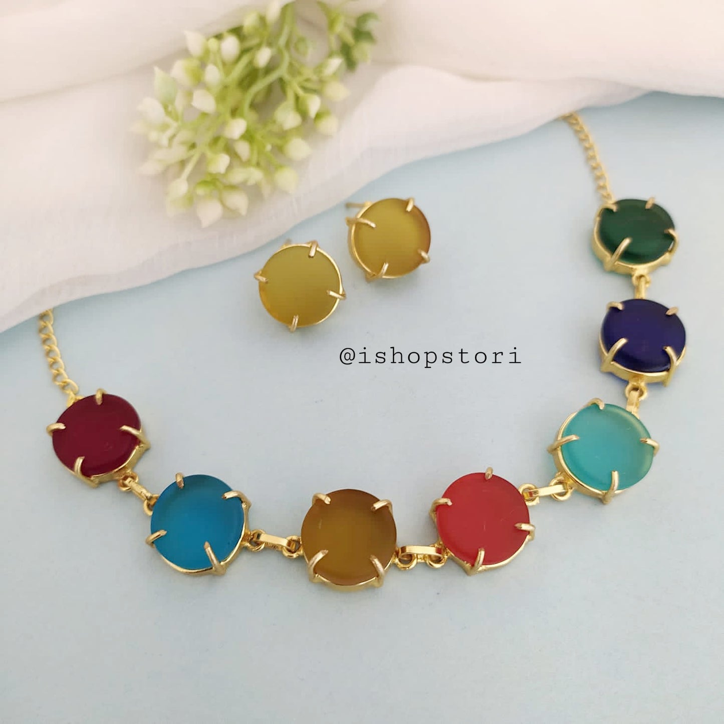 Multi-color raw stone claw necklace in a stylish design with gold earrings.