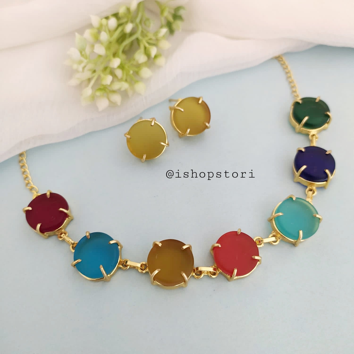 Multi-color raw stone claw necklace in a stylish design with gold earrings.